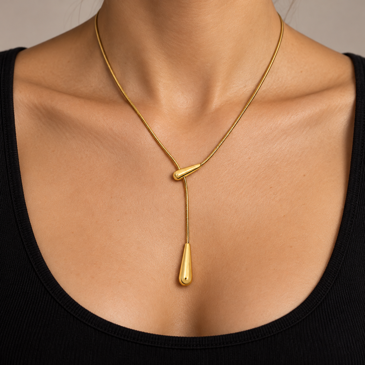 Gold-tone Y-shaped lariat necklace with a delicate chain, polished teardrop slider, and elongated teardrop pendant.
azzaik.com