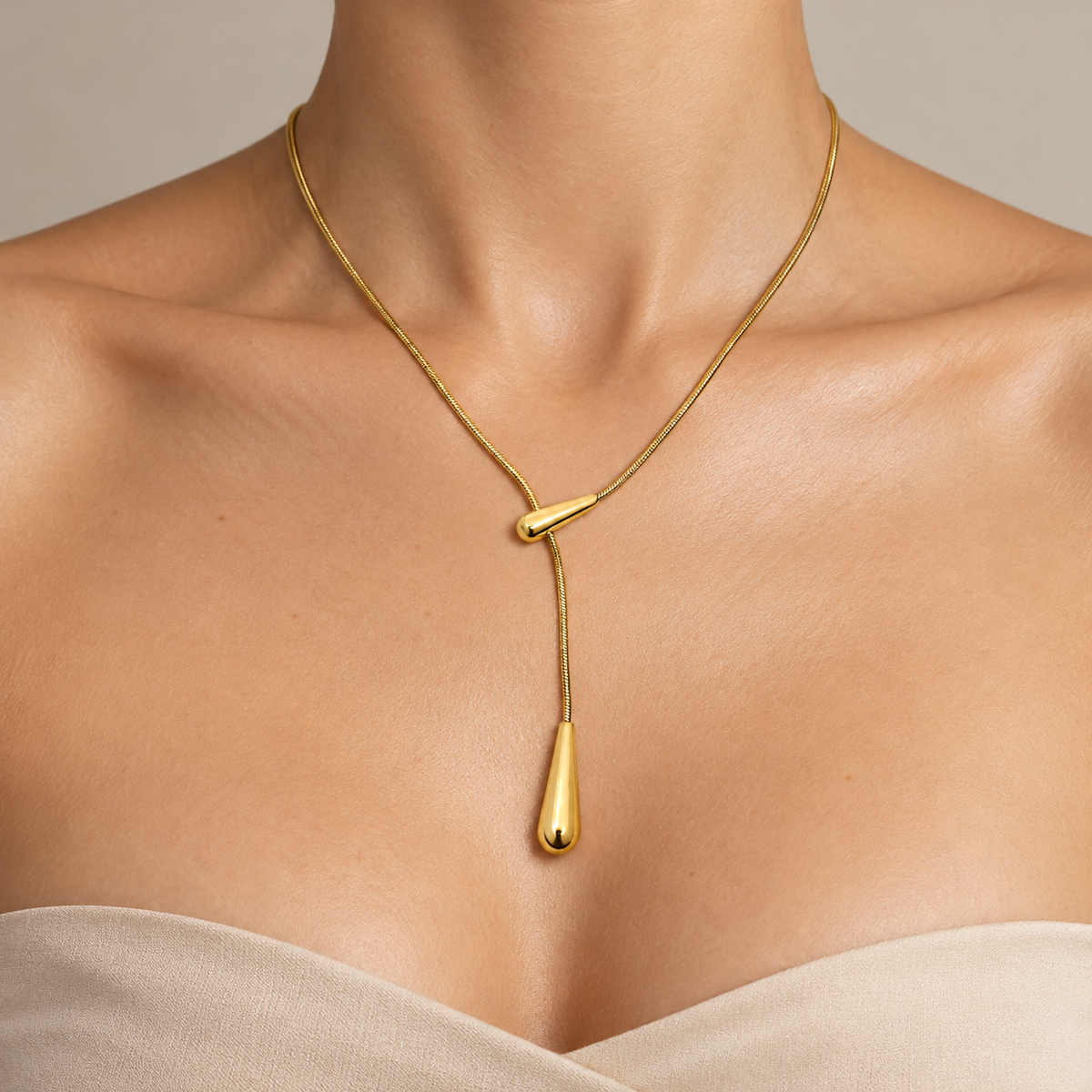 Gold-tone Y-shaped lariat necklace with a delicate chain, polished teardrop slider, and elongated teardrop pendant.
azzaik.com