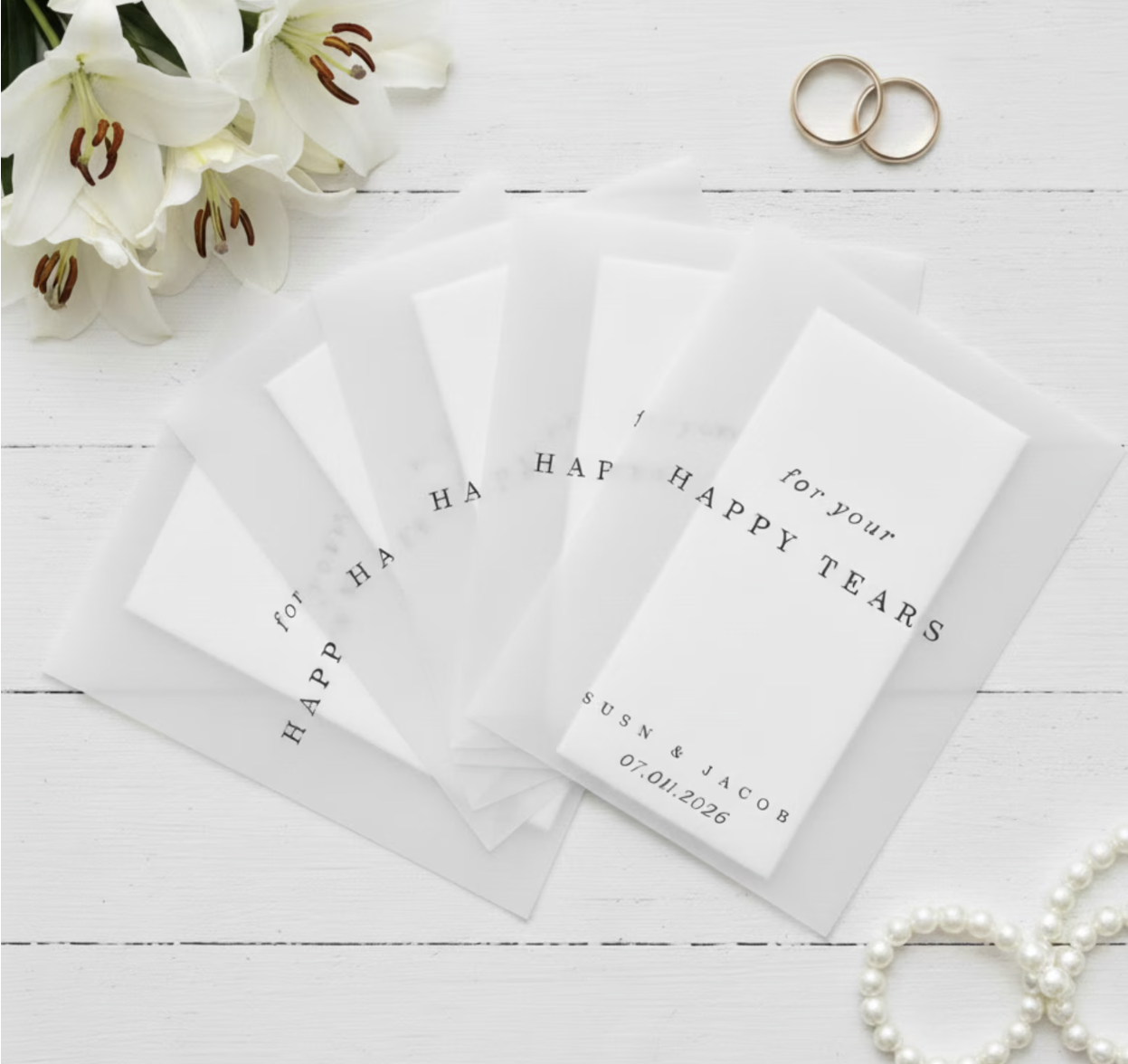 Set of cards with 'Happy Tears' text on a white wooden surface with flowers and rings.