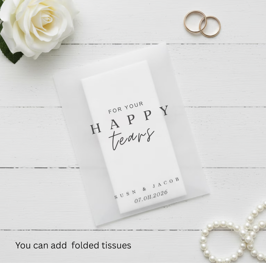 Personalized tissue pack with 'For your happy tears' text on a white wooden surface with flowers and rings.