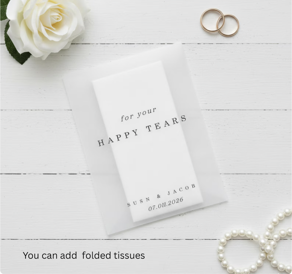 Wedding tissue packet with personalized text on a white wooden surface with a rose and rings.